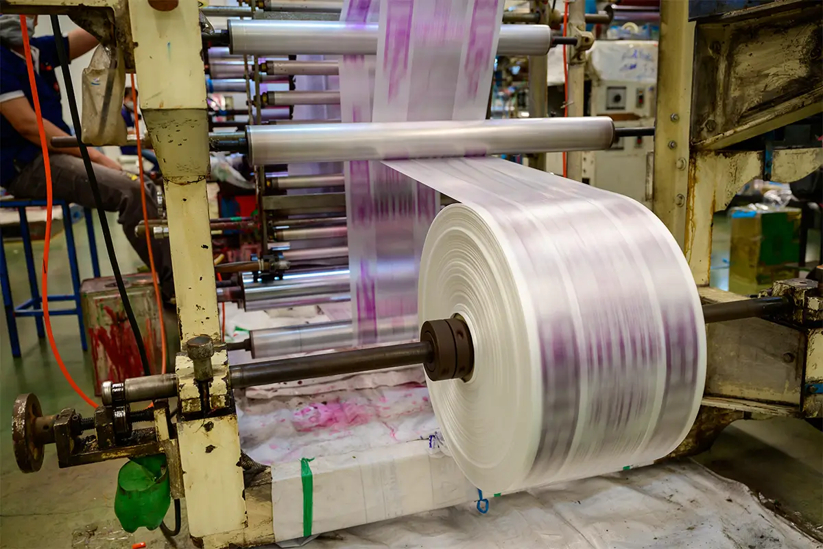 A close-up of the polyethylene coating process on a paper roll.